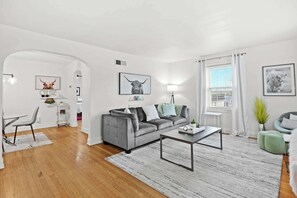 Un salon moderne avec un canapé gris, une table basse et un coin repas comprenant une chaise et une table.