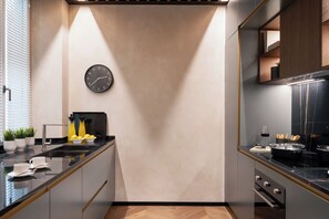 A modern kitchen with a black clock, a sink, and a stove. - Arts & Crafts Apartments (Florence)