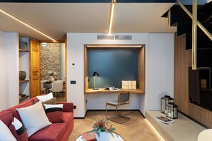 A modern living room with a red sofa, a wooden desk with a computer, and a stone wall. - Arts & Crafts Apartments (Florence)