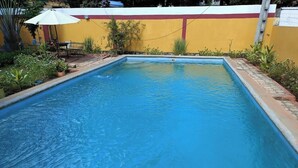 Una piscina rectangular con borde de azulejos, rodeada por un bajo muro de ladrillo.