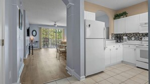 A modern kitchen with white cabinetry, a refrigerator, and a coffee maker. - River Crossing Unit 324 (North Myrtle Beach)