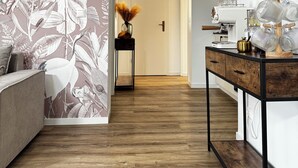 A modern interior with a wooden floor, a sofa, a coffee table, and a wall with a nature-themed mural. - Zinna Monastery Post Office (Jüterbog)