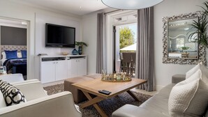 Un salon moderne avec un canapé, une table basse et un téléviseur. Il y a également un coin cuisine avec des placards et une table à manger.
