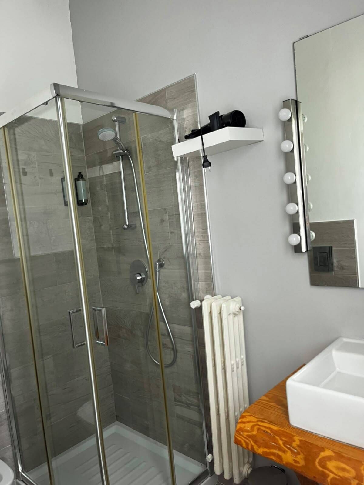 A modern bathroom with a glass-enclosed shower, a white sink, and a vanity with a mirror.