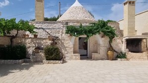 A stone building with a conical roof and two chimneys.