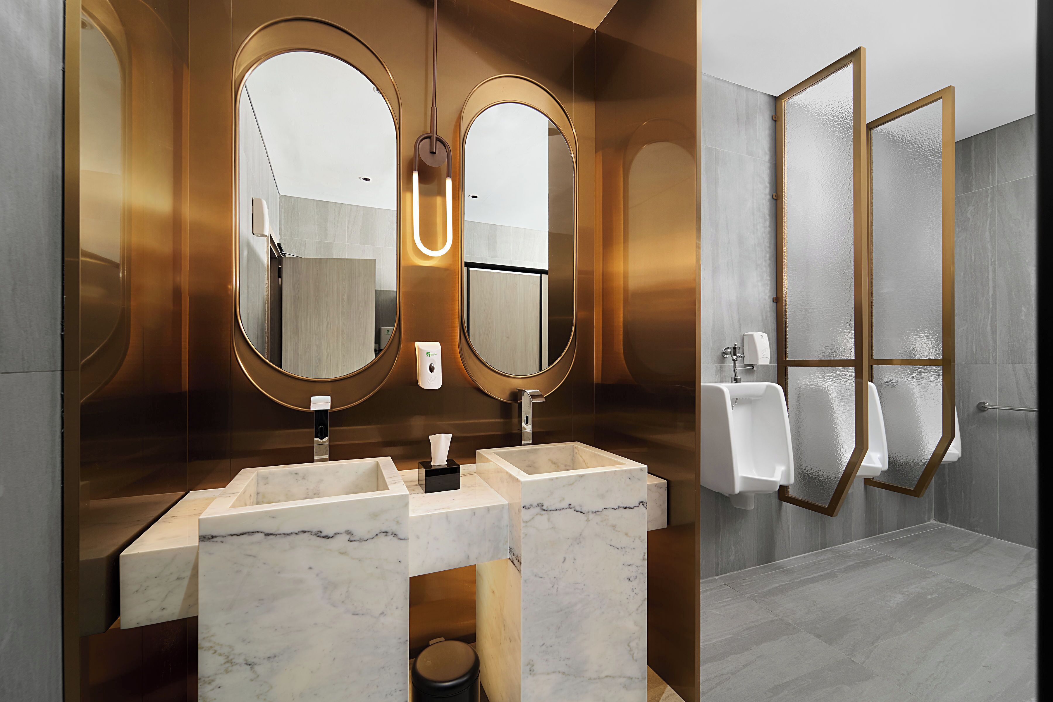 A modern bathroom with two marble sinks, large mirrors, and a glass shower enclosure.