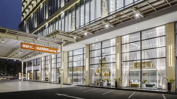 Un hotel moderno con amplios ventanales, un acceso cubierto y un cartel de Harris Suites.
