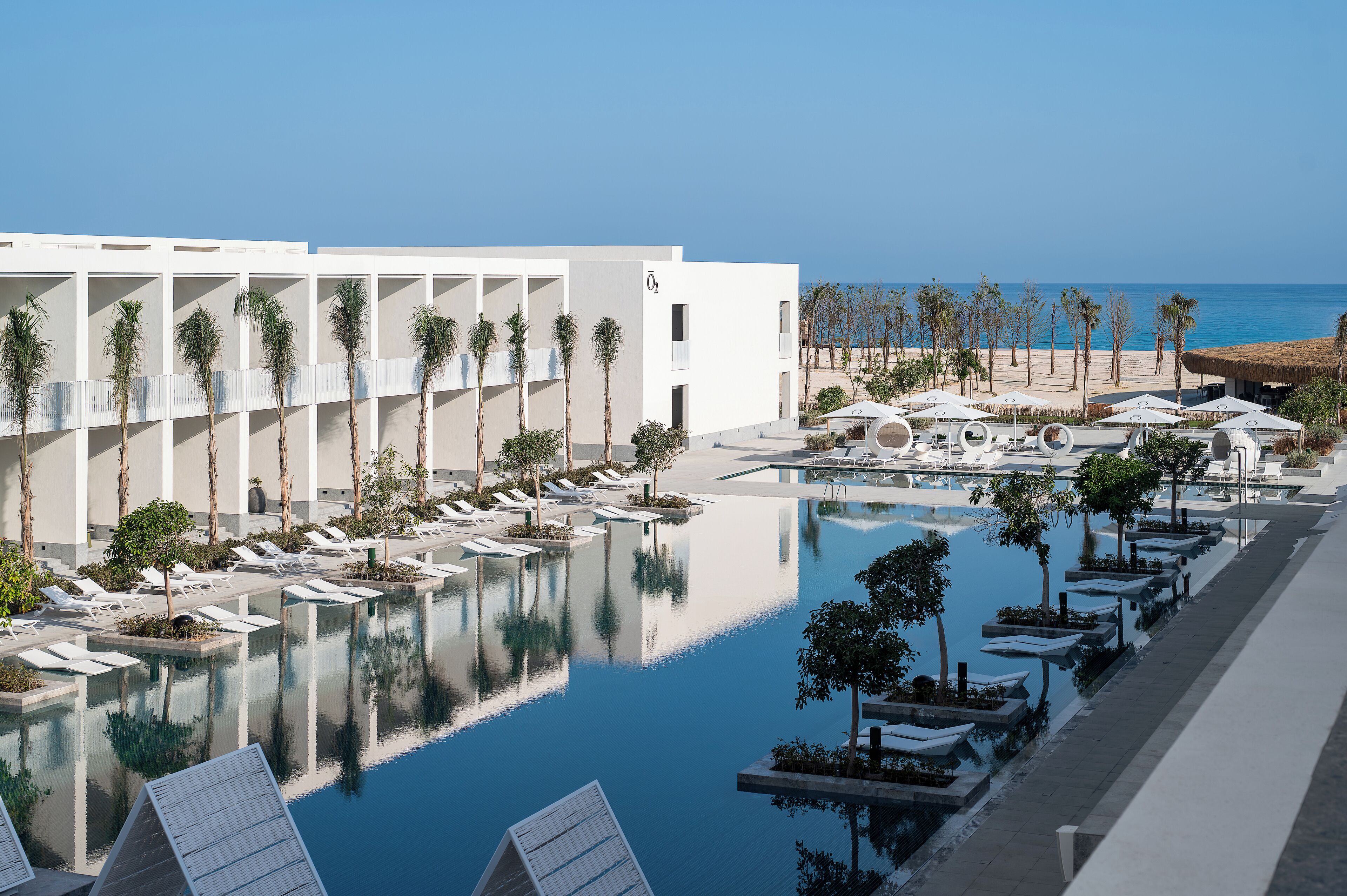 Ein Resort mit Pool, Liegestühlen und Blick auf den Strand.