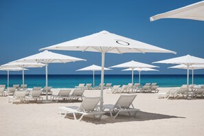 Praia particular, areia branca, espreguiçadeiras, guarda-sóis 