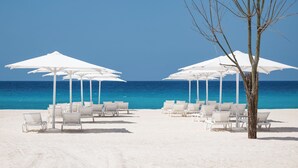 A beach with white umbrellas and lounge chairs facing the ocean. - My Ōtel North Coast (El Dabaa)