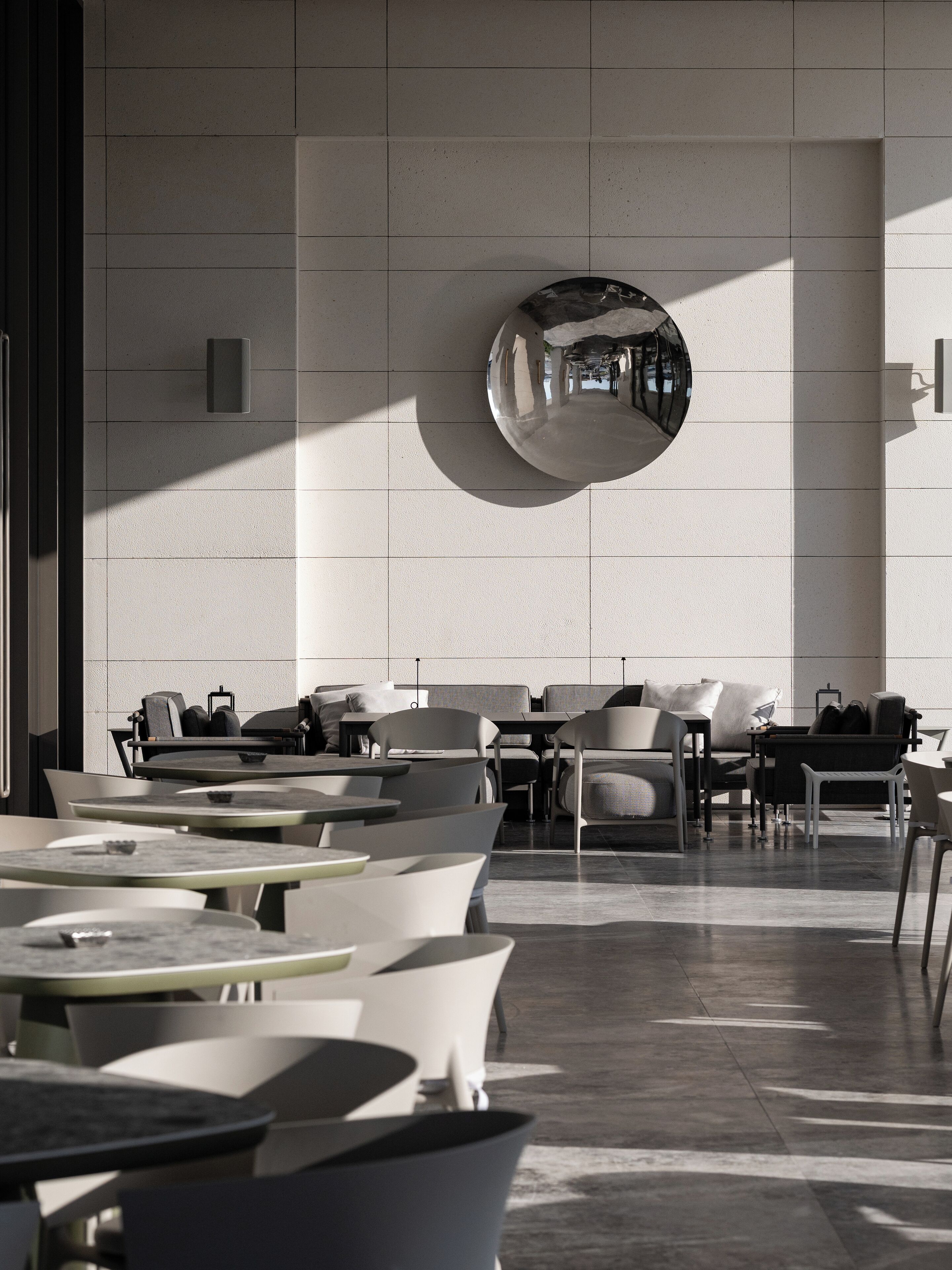 Un espacio interior moderno con mesas y sillas, un llamativo elemento decorativo en la pared y un diseño limpio y minimalista.