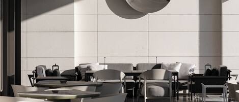 A modern indoor seating area with tables and chairs, a large reflective wall feature, and a clean, minimalist design.
