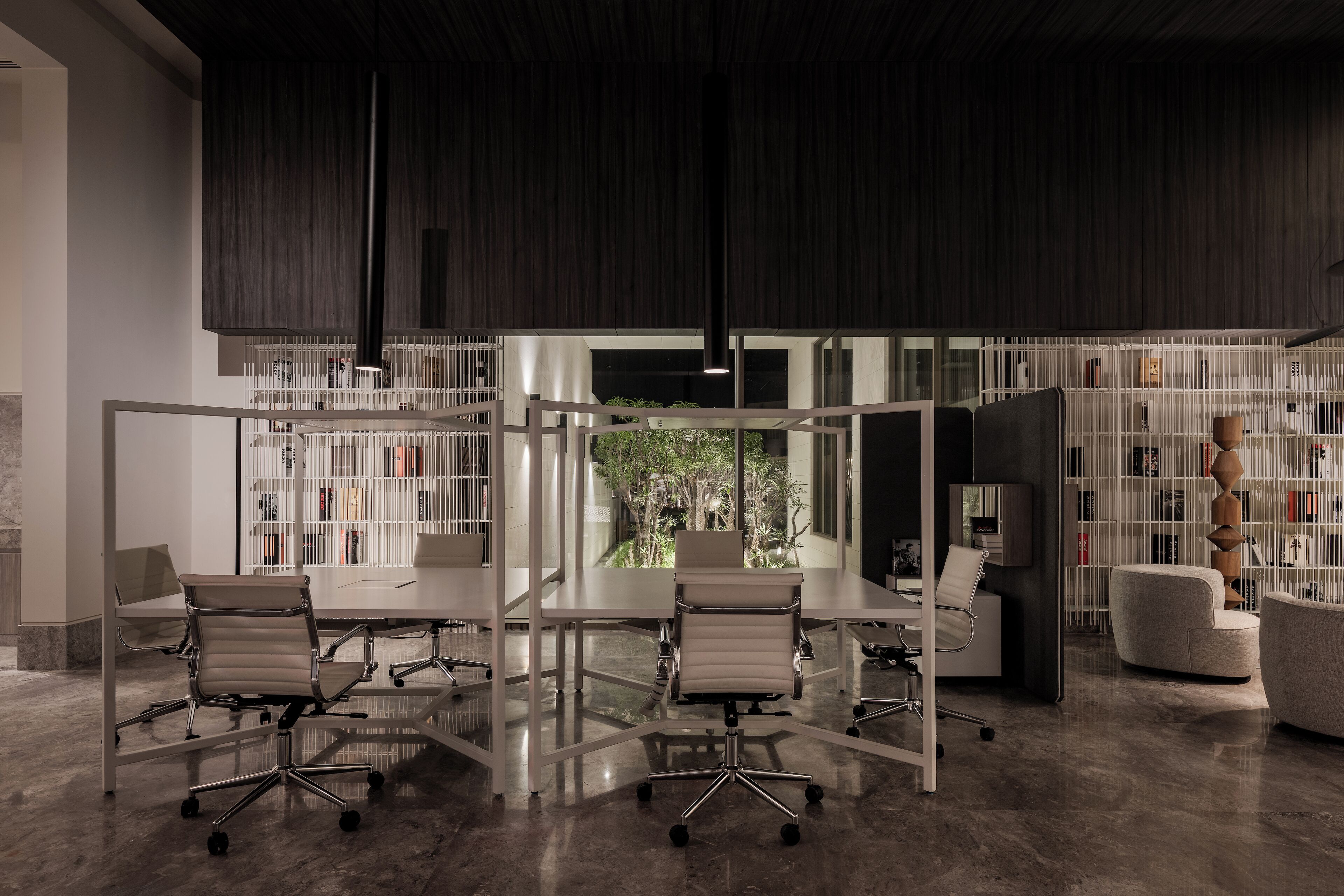 Un espace de bureau moderne avec une cloison en verre, du mobilier blanc et une vue sur la verdure.