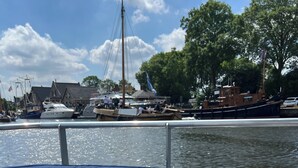 Un pont de bateau avec deux verres contenant une boisson rose, un verre d’eau et un salier posés sur une table.