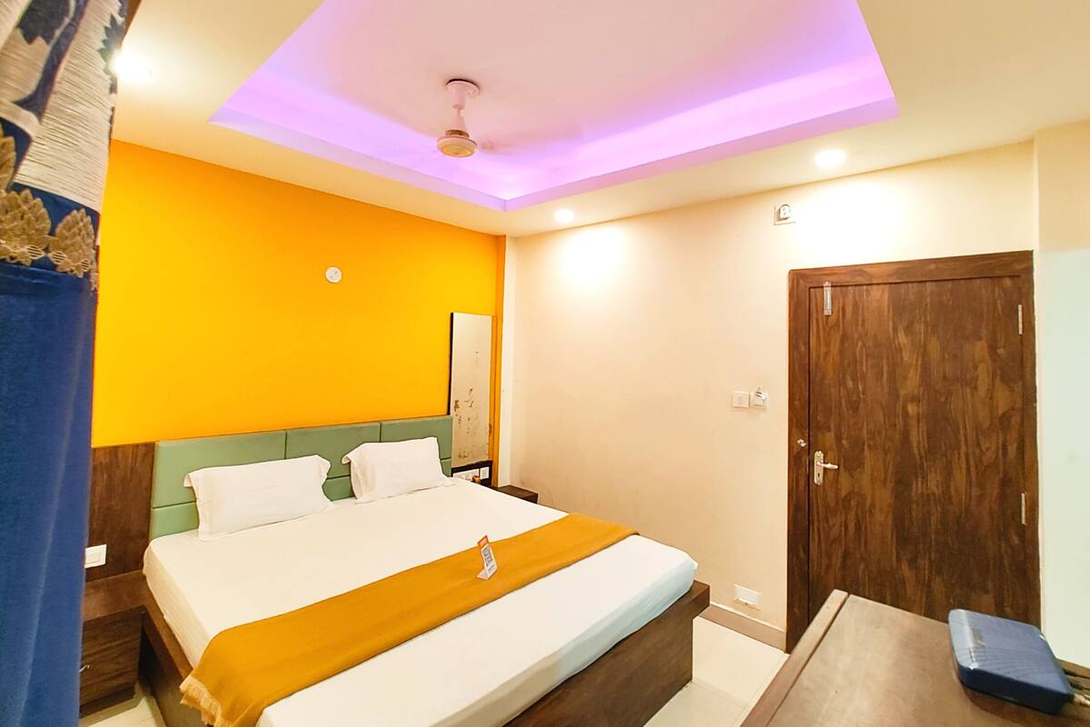 Une chambre d’hôtel avec un lit, une armoire en bois et un bureau avec une chaise.