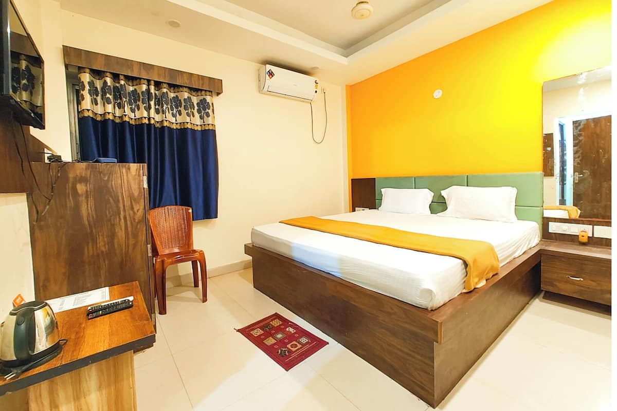 Une chambre d’hôtel comprenant un lit, un bureau en bois, une chaise, un climatiseur et un miroir.