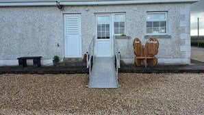 A building with a white exterior, a metal ramp leading to a door, and two wooden signs reading "Nods" and "Cottage". - Tranquil Cottage Retreat in Kells, Leitrim (Mullagh)