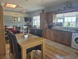 Una cocina moderna con armarios de madera, un comedor con mesa y sillas, lavadora integrada y un ventanal con vistas.