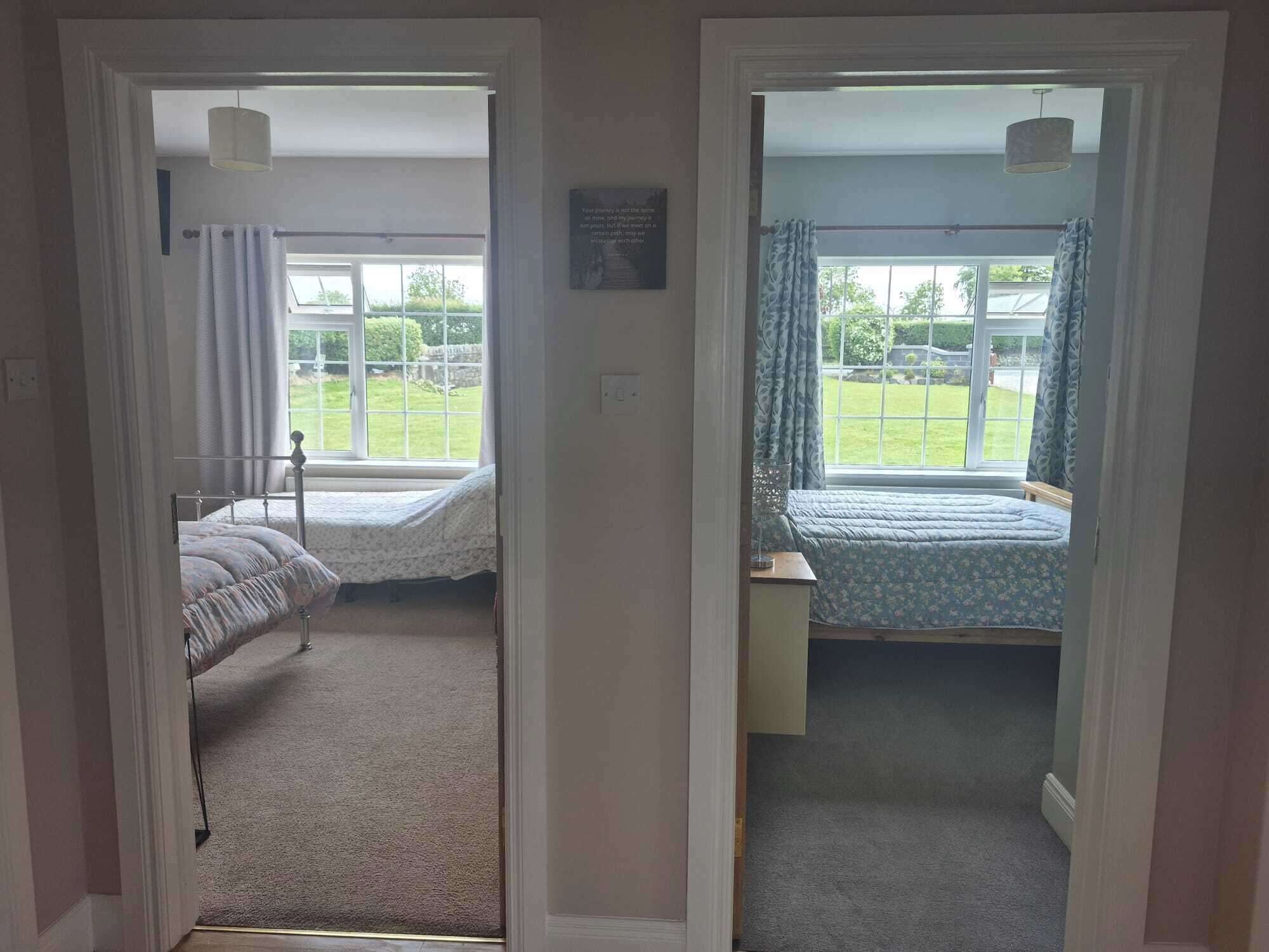 Un dormitorio con dos camas, una ventana y una puerta que da a otra habitación.