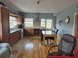 A kitchen with wooden cabinets, a dining table, and a red chair.