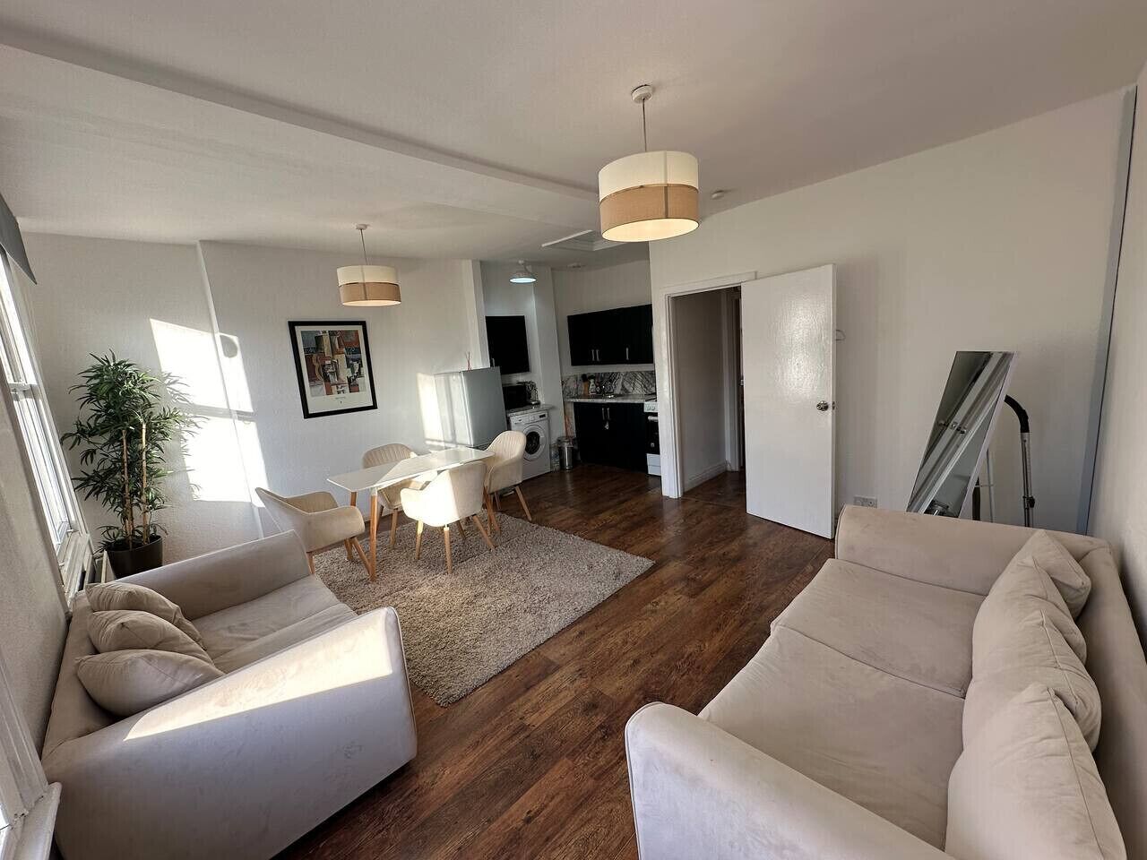 Una sala moderna con un sofá, una mesa de comedor y una cocina al fondo.