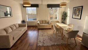 A spacious living area with a sofa, a dining table with chairs, and a large window providing a view of the city. - Quiet, Clean & Peaceful 1Bed Flat near Paddington (Greater London)