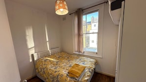 A bedroom with a bed, a window, a radiator, and a hanging light fixture. - Quiet, Clean & Peaceful 1Bed Flat near Paddington (Greater London)