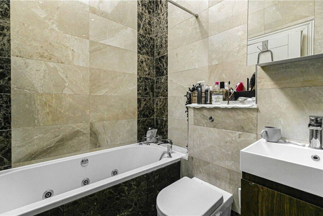 Een badkamer met een bad, toilet en een wastafel met spiegel.