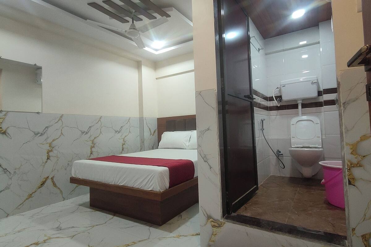 A hotel room with a bed, a shower, and a toilet.