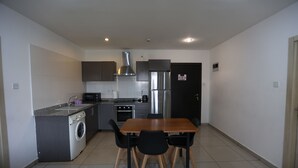 A compact kitchen with a washing machine, microwave, stove, and stainless steel refrigerator.
