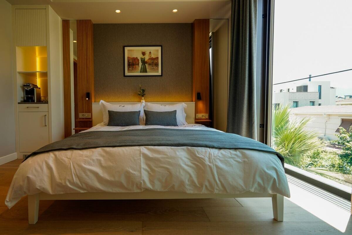 Quarto de hotel com uma cama grande, um quadro na parede e vista para edifícios.