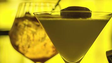 Un verre à martini, garni d’une tranche de citron et muni d’une paille, posé sur une table devant un arrière-plan flou.
