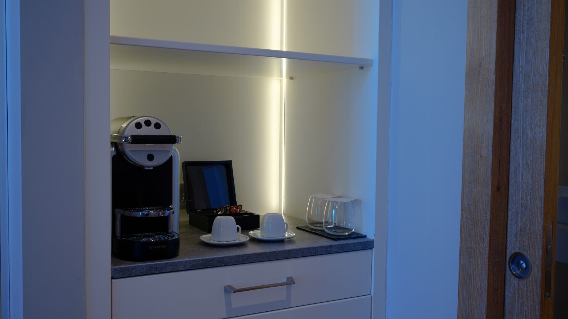 Una kitchenette equipada con una cafetera, un refrigerador pequeño, un microondas y una máquina de café.