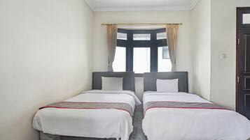 A double room with two beds, a window with curtains, and a door.