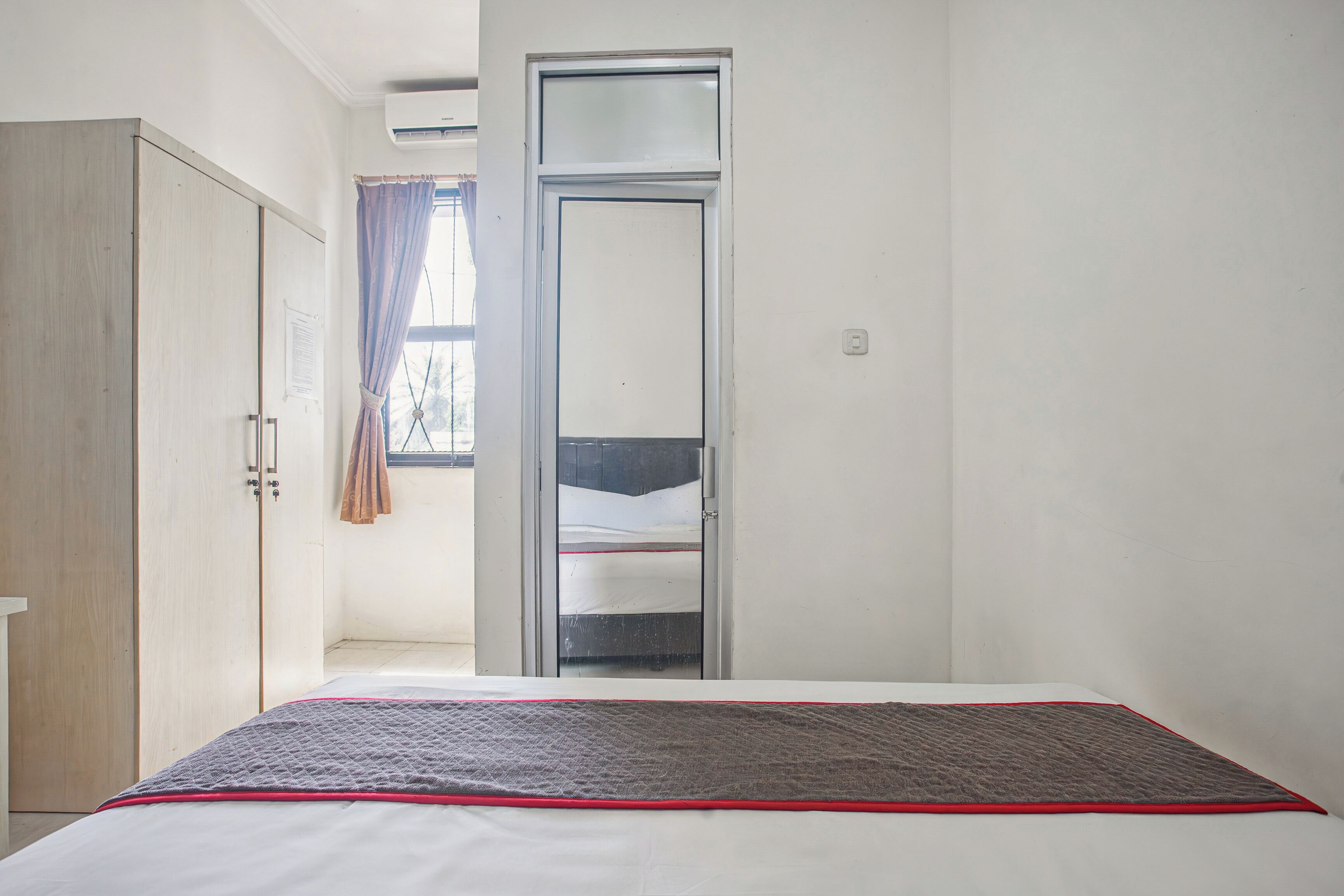 A bedroom with a bed, a wardrobe, and a sliding door leading to a balcony.