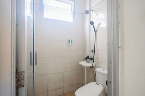Een kleine, schone badkamer met een douche, toilet en wastafel.