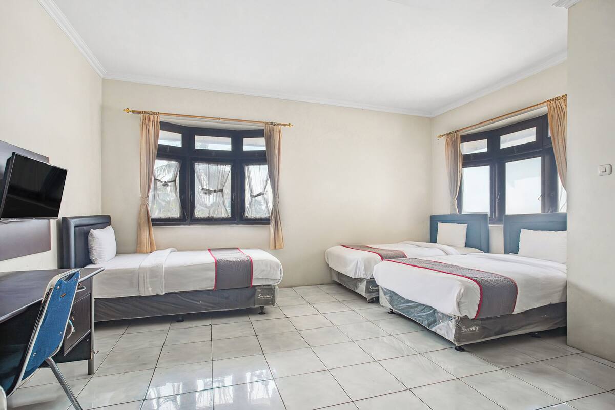 Una habitación de hotel con dos camas, un escritorio y una televisión.