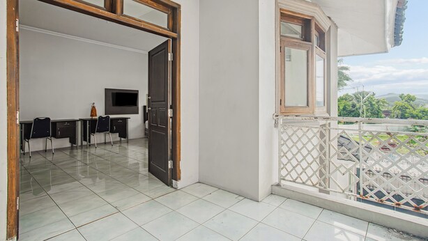 Ein geräumiges Zimmer mit Balkon, einer Essecke mit Stühlen und einem Tisch sowie einem Fernseher.