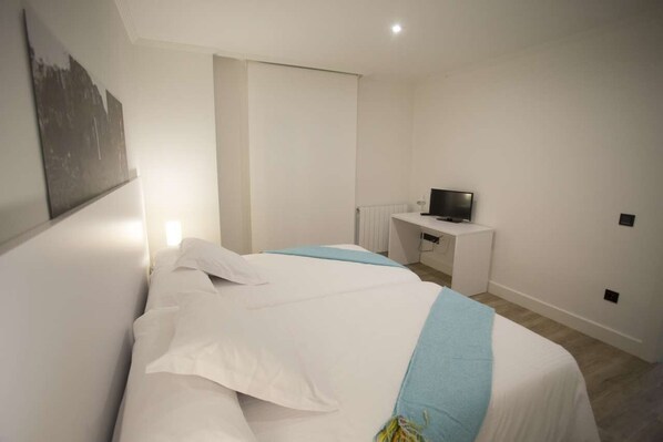 A bedroom with a bed, a TV on a small table, and a wall-mounted artwork.