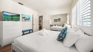 Un dormitorio con cama, televisión y obras de arte en las paredes.