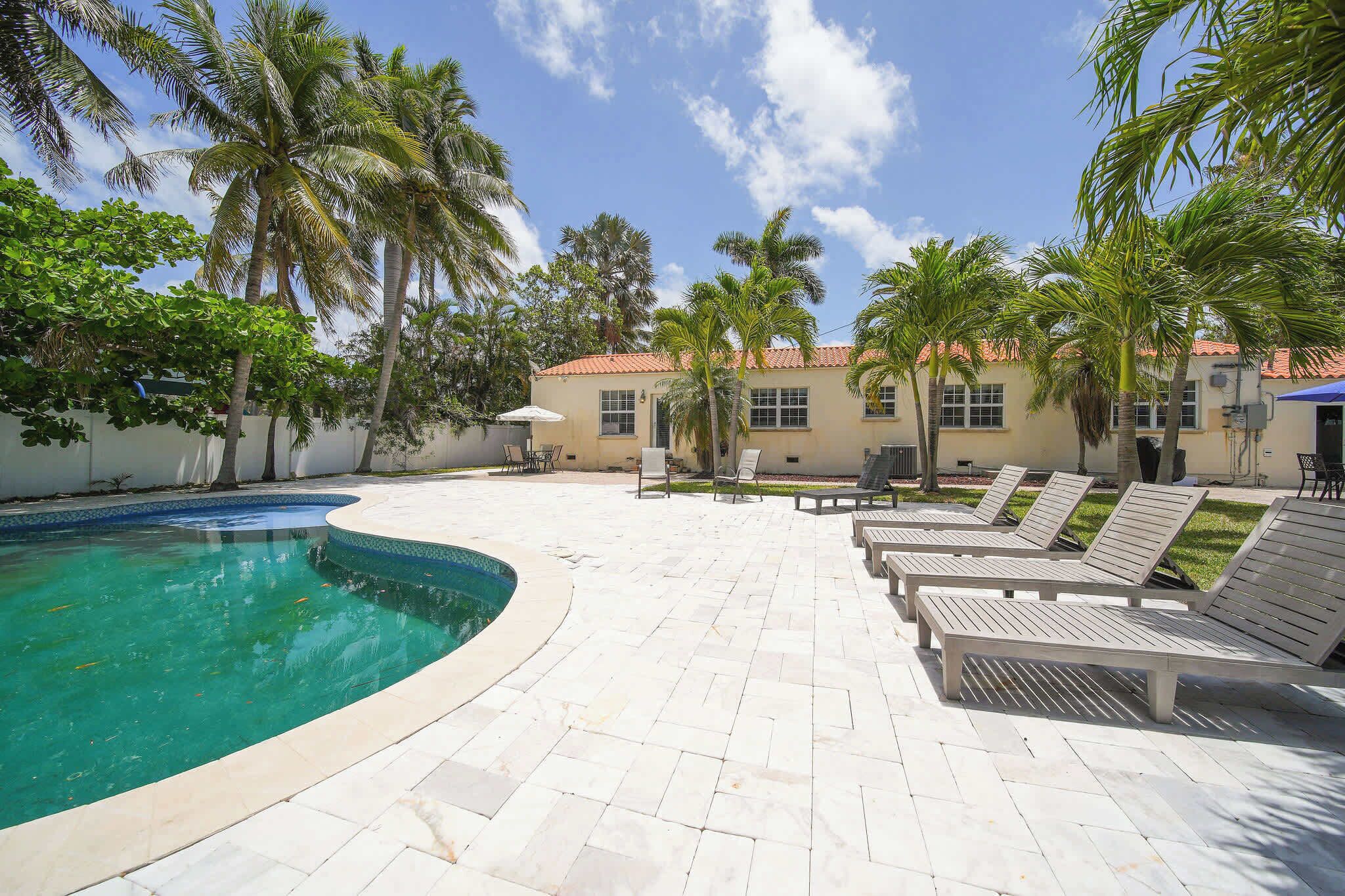 A pool area with lounge chairs and palm trees.