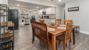 A modern kitchen with white cabinets, a black refrigerator, and a dining area with a wooden table and chairs. - 12m to Belton<br>Outdoor dining<br>Long Stays welcome<br>Huge fully stocked kitchen<br>Master Suite<br>On-site laundry<br>Utilities included<br>Fuller furnished<br>Natural light<br>Block out shades (Grandview)