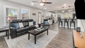 A modern living room with a leather sofa, a coffee table, and a dining area with bar stools. - 12m to Belton<br>Outdoor dining<br>Long Stays welcome<br>Huge fully stocked kitchen<br>Master Suite<br>On-site laundry<br>Utilities included<br>Fuller furnished<br>Natural light<br>Block out shades (Grandview)