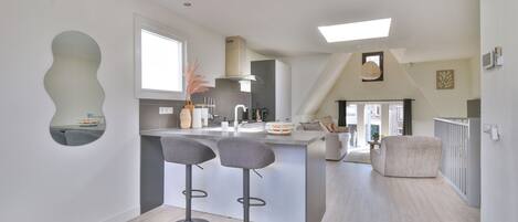 A modern kitchen with a central island, bar stools, and a dining area with a chair.