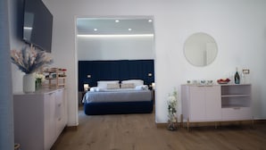A modern bedroom with a bed, bedside tables, a dresser, a mirror, and a television.