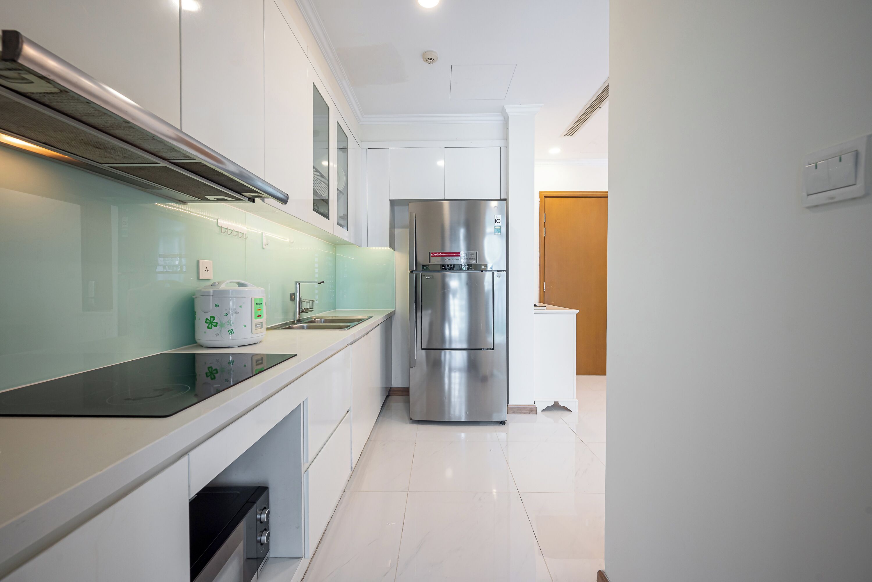 A modern kitchen with white cabinetry, a stainless steel refrigerator, and a built-in oven.