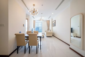 A modern living room with a dining area, a large mirror, and a chandelier.