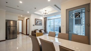 A modern dining area with a large table and chairs, a kitchen with a stainless steel refrigerator, and a balcony with a view. - PD Pristine Apartment Landmark Plus (Ho Chi Minh City)