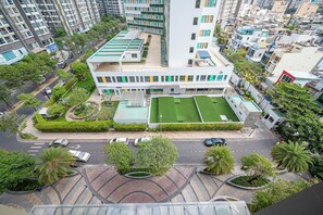 A modern building with multiple floors, surrounded by greenery and a parking area.