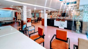 A modern hotel lobby with a reception desk, seating area, and a kitchen visible through a glass partition. - Hotel Apex Intercontinental (Jaipur)